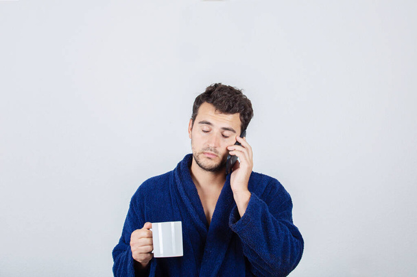 Retrato de jovem sonolento cabelo bagunçado, usa roupão de banho azul, dr
 - Foto, Imagem