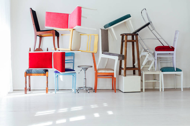 muchas sillas multicolores de pie en la habitación blanca
 - Foto, Imagen