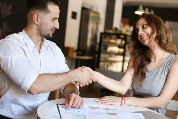 Successful businessman and woman working with documents, shaking hands. - Photo, Image