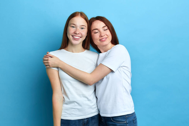 Two beautiful best friends hugging while standing in the studio - Фото, изображение
