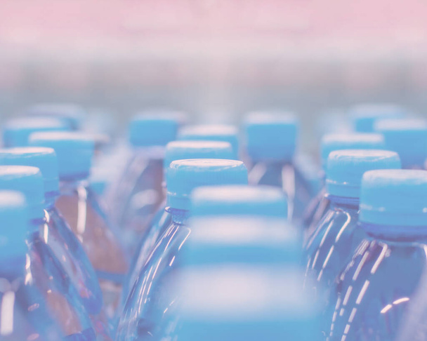 Desenfoque de fondo, tapas azules conjunto de agua embotellada. Agua potable pura en botellas de plástico azul
 - Foto, Imagen