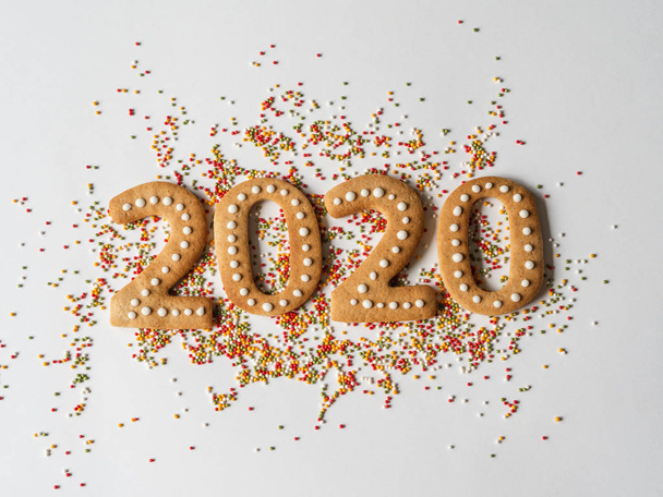 Mehrfarbiger Teigzucker und Lebkuchen in Form von Ziffern 2020 auf weißem Hintergrund. Ingwerkekse für das neue Jahr 2020 - Foto, Bild