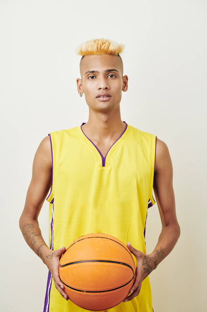 Portrait of handsome slim Black basketball player posing with ball against white background  - Foto, imagen