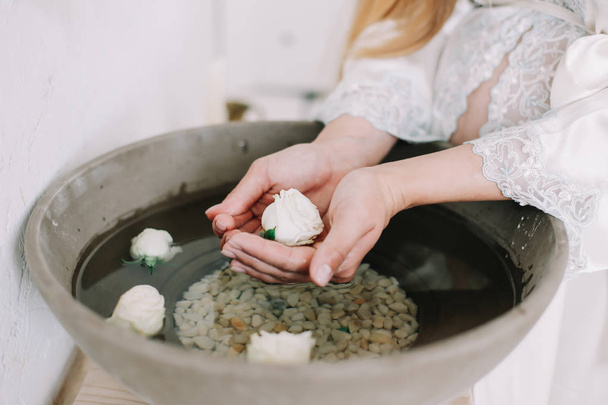 Hands of a girl holding flowers in a vintage sink with water. Retro stoned basin. - Foto, Imagem
