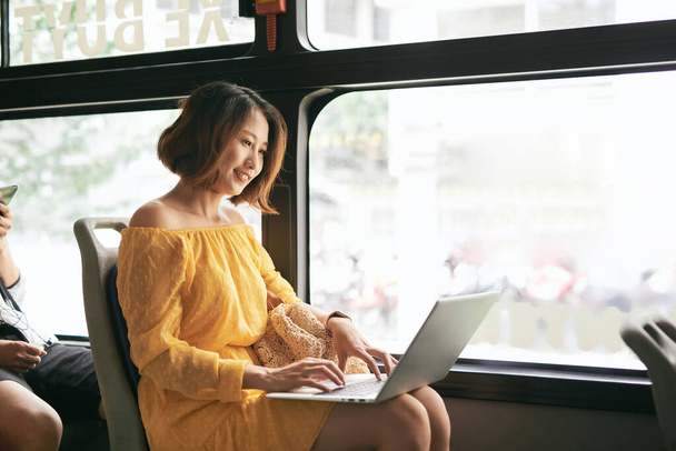 Jonge zakenvrouw op zakenreis. Werken op de bus met haar laptop. - Foto, afbeelding