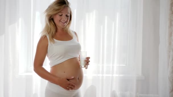 Ernährung von Milchprodukten während der Schwangerschaft, zukünftige Mama hält Glasmilch und lächelt - Filmmaterial, Video