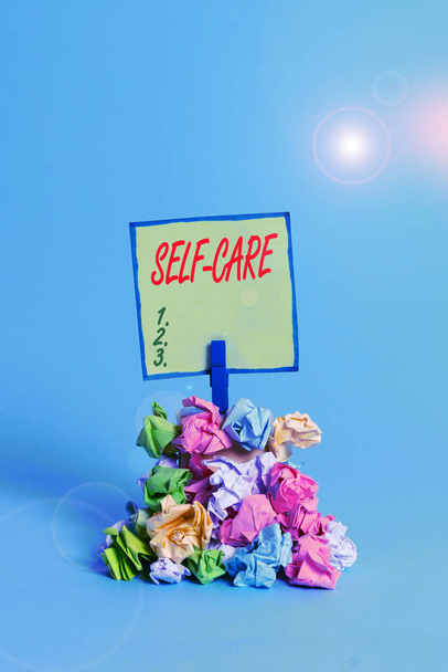 Conceptual hand writing showing Self Care. Business photo text practice of taking action preserve or improve ones own health Reminder pile colored crumpled paper clothespin wooden space. - Photo, Image