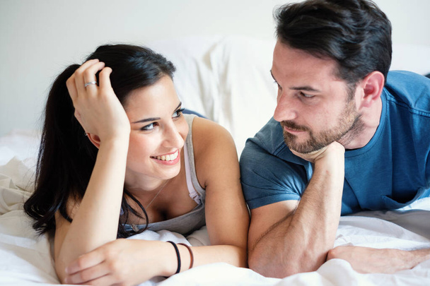 Love couple lying in bed kissing and looking each other - Photo, Image