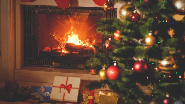 getinte kerst achtergrond met kerstcadeaus en cadeautjes dozen onder kerstboom en brandende open haard - Foto, afbeelding