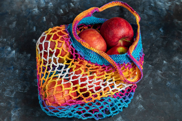 Ecological cotton mesh for carrying and storing products. Durable, bright. In a mesh bag are fruits. Red apples. View from above. On a bright background. Copy space.  - Photo, Image