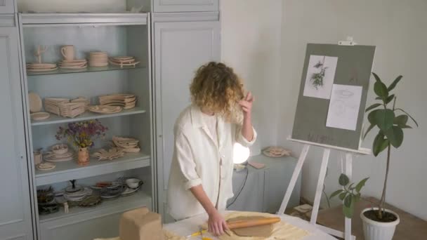 inspiring occupation, artisan potter female rolls clay on table using rolling pin for making ceramic dishes and dancing at workroom - Video