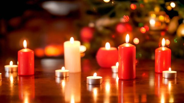 Όμορφο χριστουγεννιάτικο φόντο με καύση λευκό και κόκκινο κεριά σε ξύλινο τραπέζι - Φωτογραφία, εικόνα