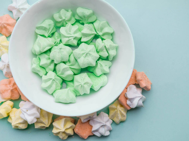 Ceramic bowl full of colorful merengues at pastel mint background - Photo, Image