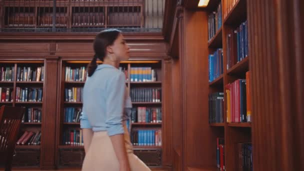junge Studentin am Bücherregal drinnen - Filmmaterial, Video