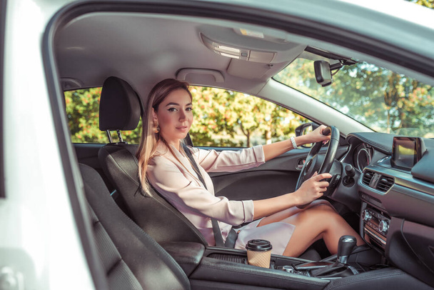 woman wheel of car machine. In summer autumn city. Business lady driving. Background trees. Beautiful girl everyday makeup. Business class sedan. Car sharing in city car rental. - Foto, Bild