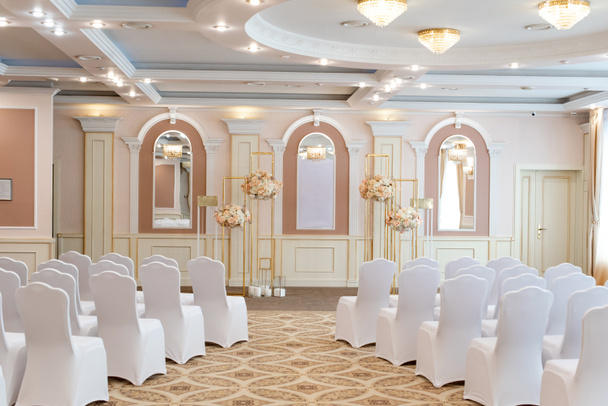 Gyönyörű esküvői terem fehér székekkel a vendégek számára. Fényes és stílusos dekoráció - Fotó, kép