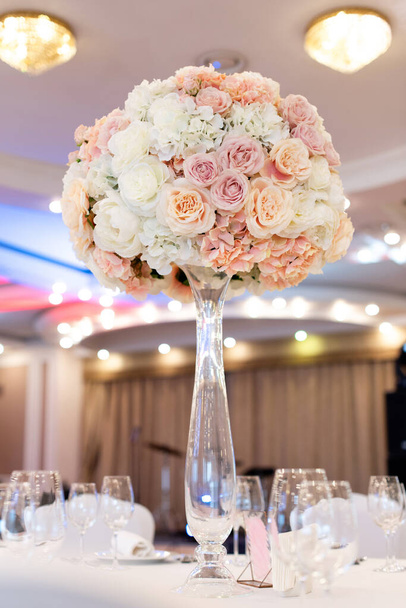 Hochzeitsblumen auf einer hohen Glasvase. Hochzeitsdekor in Pastelltönen. - Foto, Bild