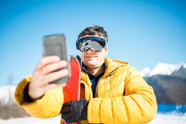 Photo of smiling man in ski mask taking pictures of himself in afternoon. - Foto, afbeelding