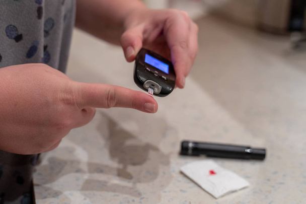 Femme utilise lancette pour piquer doigt pour le test de glycémie à la maison
 - Photo, image
