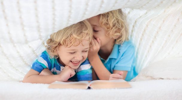Детская книжка в постели. Дети читают книги
. - Фото, изображение