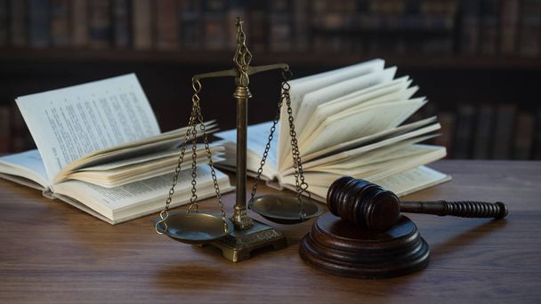 Символи Закону і правосуддя на дерев'яному столі з розмитими книгами.. - Фото, зображення
