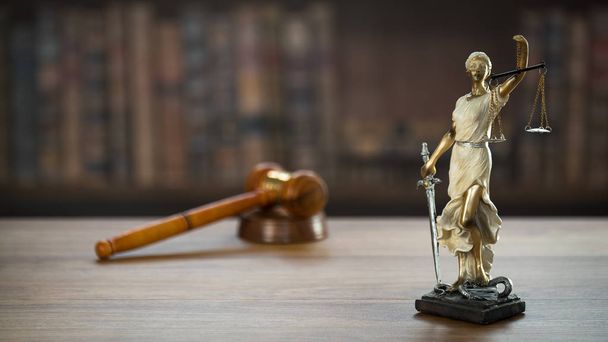 Symbole prawa i sprawiedliwości na drewnianym stole z zamazanym tłem książek. - Zdjęcie, obraz