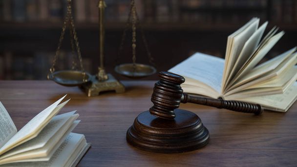 Símbolos de Ley y Justicia sobre mesa de madera con fondo de libros borrosos
. - Foto, Imagen