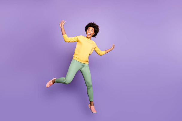 Full length photo of amazed excited teenager mulatto girl have fun autumn fall holidays greet friends feel crazy like child jump scream wear casual style outfit isolated violet purple color background - Foto, Imagem