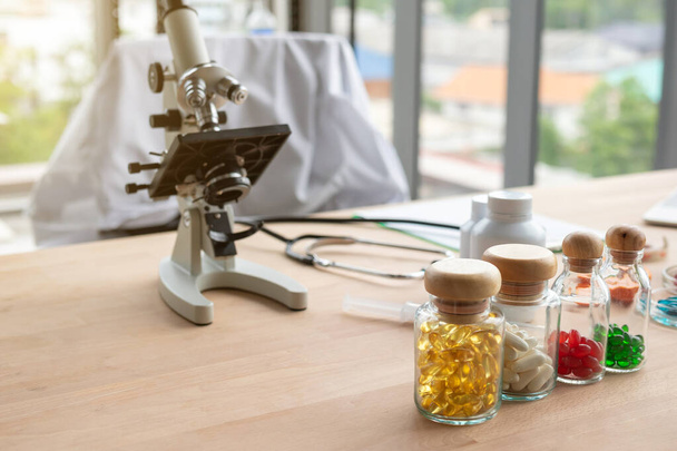 Medicine bottle and microscope on doctor's table - Foto, afbeelding