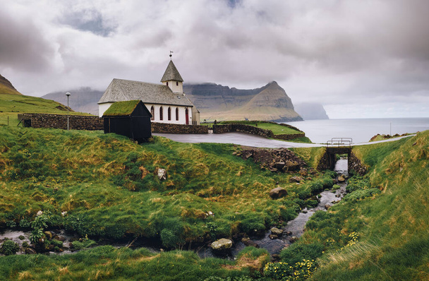 Μικρή εκκλησία του χωριού στην ακτή της θάλασσας στο Βιδαρείδι, Νησιά Φερόε, Δανία - Φωτογραφία, εικόνα