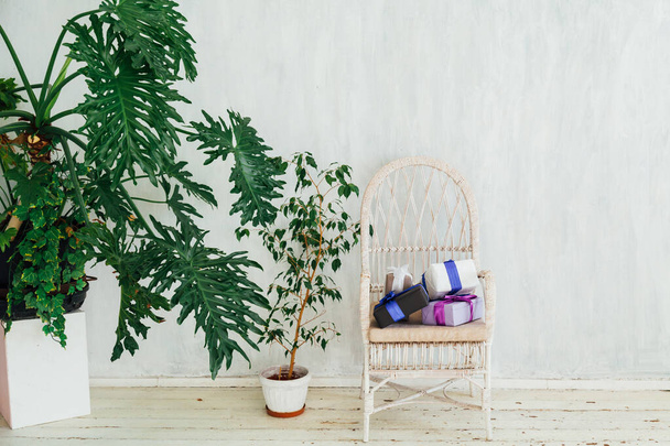 cadeira branca com plantas e presentes na sala cinza
 - Foto, Imagem