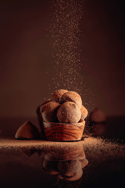 Suklaa tryffelit pieni puinen ruokalaji sirotellaan kaakao pow
 - Valokuva, kuva