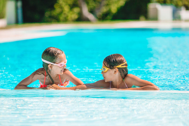 Adorable little girls playing in outdoor swimming pool on vacation - Zdjęcie, obraz
