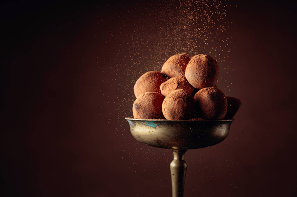 Chocolade truffels in oude koperen vaas bestrooid met cacaopoeder - Foto, afbeelding