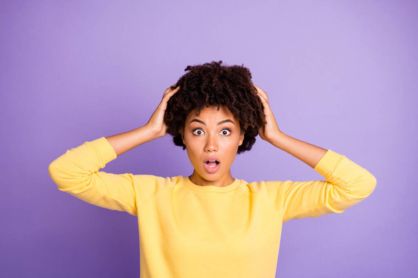 Photo of curly wavy scared frightened horrified brunette touching her hair observing them falling off expressing terrible emotions on her face feeling dander isolated purple pastel color background - Foto, Imagen