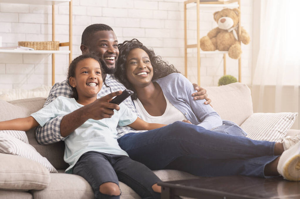 Happy black family relaxing and watching tv at home - Foto, Imagen