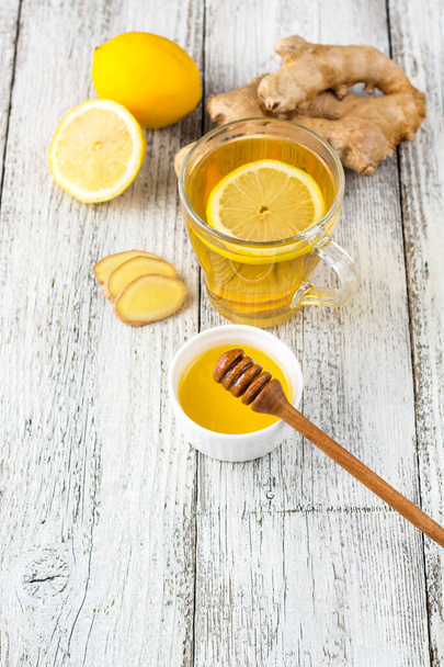 Ginger tea with lemon and honey on a white wooden background. Hot healthy winter drink - Zdjęcie, obraz