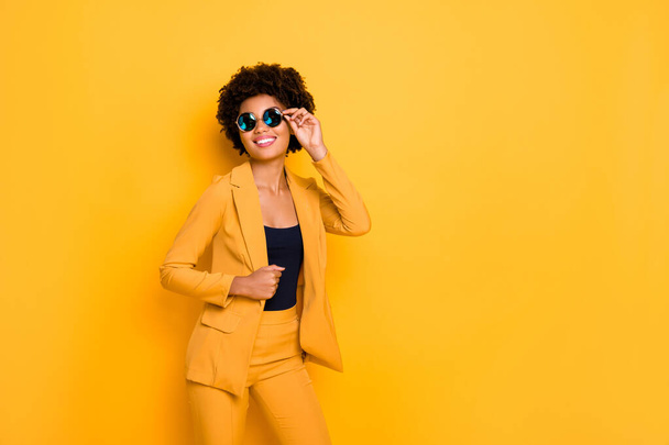 I am gorgeous. Portrait of attractive cheerful afro american lady touch her specs feel content about her beauty wear fashionable clothing isolated over yellow bright color background - Valokuva, kuva