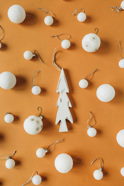 Weihnachts- / Neujahrskomposition. weiße Christbaumkugeln, Spielzeug-Tanne auf Ingwer-Hintergrund. flache Lage, Draufsicht. - Foto, Bild