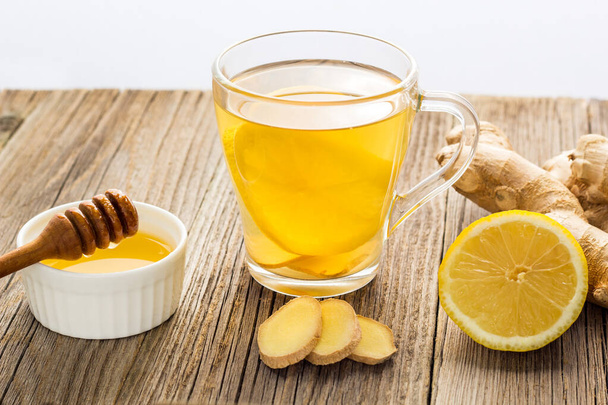 Ginger tea with lemon and honey on a wooden background. Hot healthy winter drink - 写真・画像