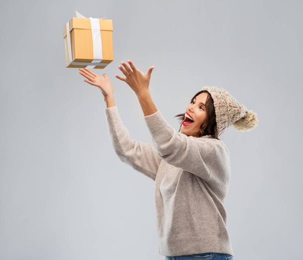 young woman in winter hat catching gift box - Foto, Imagen