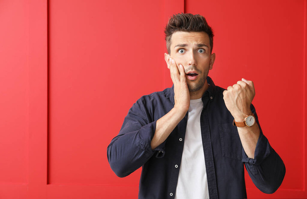 Stressé jeune homme avec montre sur fond de couleur - Photo, image