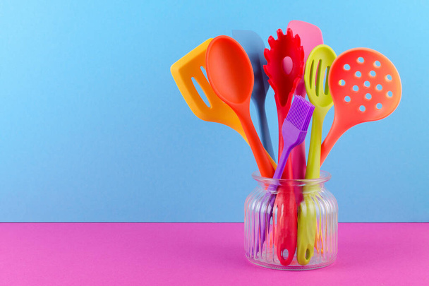 bright multi colored kitchen utensils on blue and purple background with copy space - Foto, Imagen