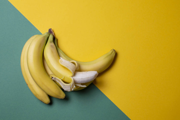 gele en groene bananen op een gekleurde achtergrond, rijp en onrijp fruitconcept - Foto, afbeelding