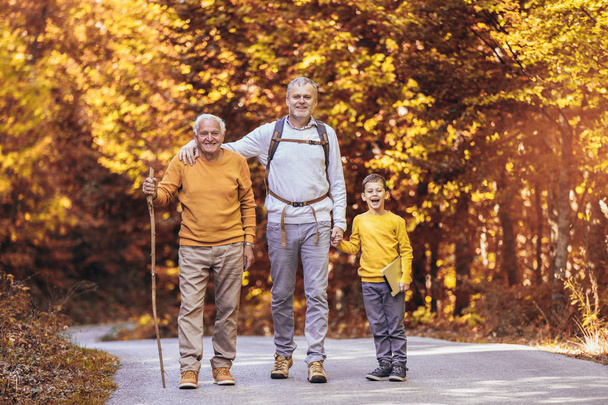 Drei-Generationen-Familie wandert gemeinsam im Herbstpark. - Foto, Bild