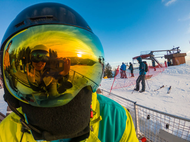 Hombre con máscara de esquí de cerca. reflexión. montañas nevadas al atardecer
 - Foto, Imagen