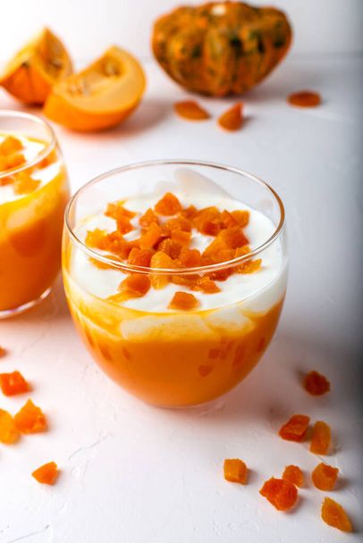 Pumpkin raw dessert. Pumpkin smoothie with yogurt and dried apricots in glasses on a white background. Autumn healthy homemade diet food. Macro. - Photo, Image