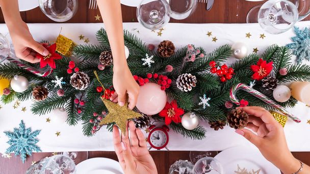 weihnachtliche Tischdekoration, Mutter-Kind-Hände reichen Sterne auf dunklem Holztisch, flach gelegt - Foto, Bild