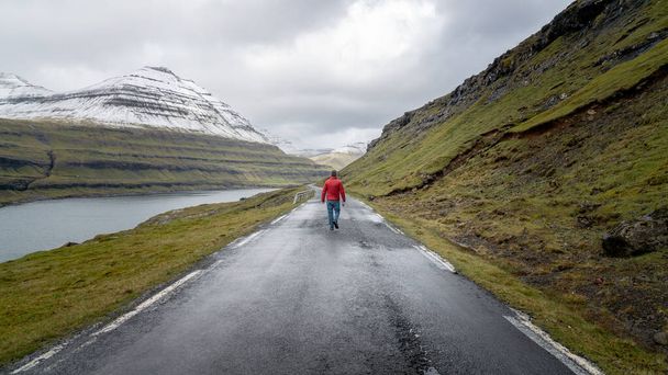 Unidentified man walking in the dramatic road landscape, Faroe Islands - Photo, Image