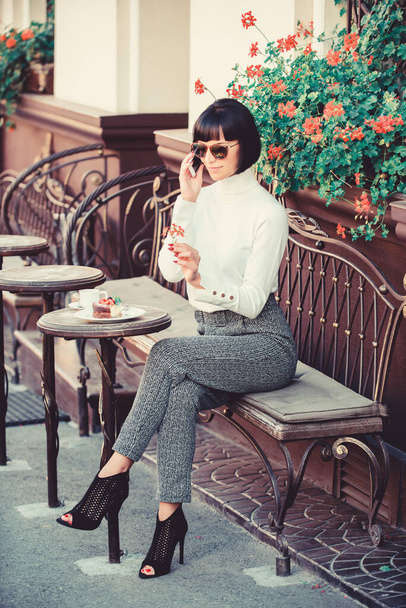 Woman attractive elegant brunette spend leisure cafe terrace background. Leisure concept. Girl fashionable lady with smartphone. Pleasant time and leisure. Relax and coffee break. Happy to hear you - Valokuva, kuva